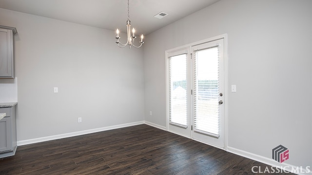 unfurnished dining area with an inviting chandelier and dark hardwood / wood-style flooring