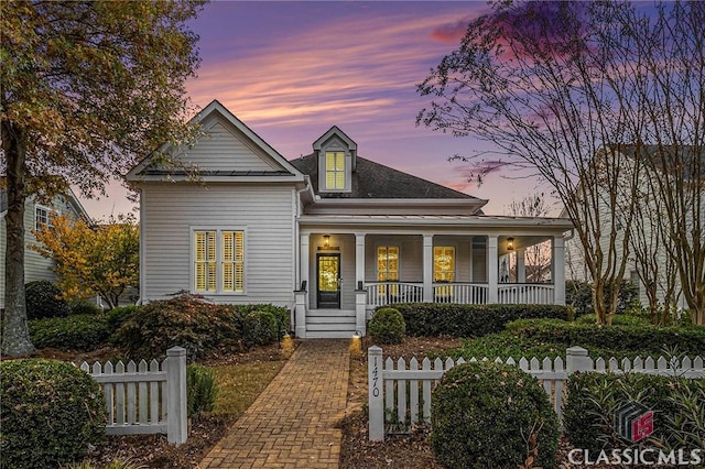 view of front of property featuring covered porch, a fenced front yard, and roof with shingles