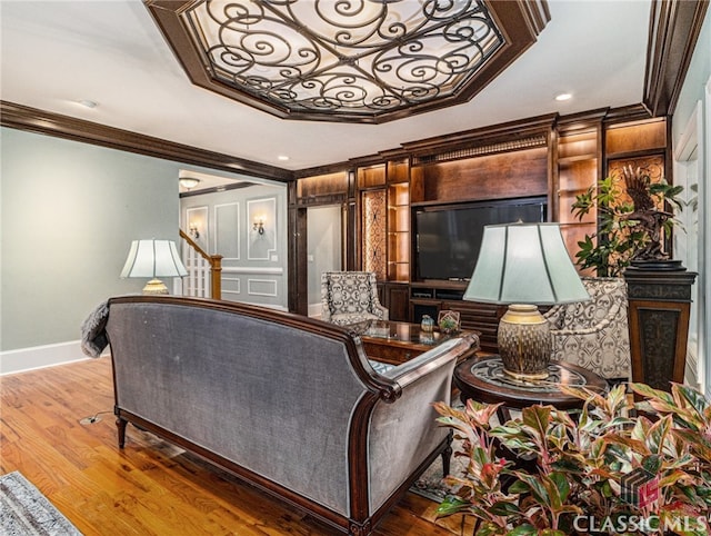 living room with a raised ceiling, hardwood / wood-style floors, and ornamental molding