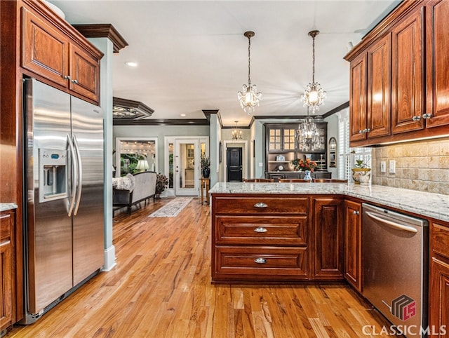 kitchen with kitchen peninsula, ornamental molding, stainless steel appliances, an inviting chandelier, and light hardwood / wood-style floors