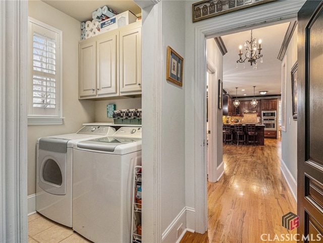 washroom with cabinets, an inviting chandelier, washing machine and dryer, light hardwood / wood-style flooring, and ornamental molding