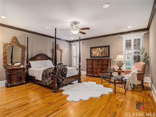 bedroom featuring crown molding, baseboards, wood finished floors, ensuite bathroom, and a ceiling fan