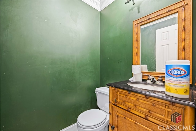 bathroom with toilet, crown molding, and vanity