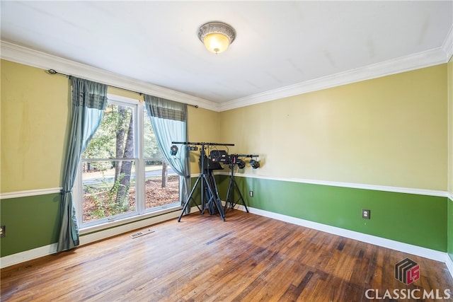 workout area featuring crown molding and hardwood / wood-style floors