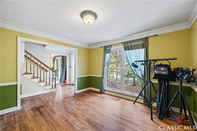 exercise area with ornamental molding and hardwood / wood-style floors