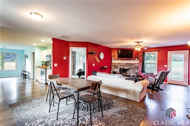 dining room featuring ceiling fan, a fireplace, and dark hardwood / wood-style floors