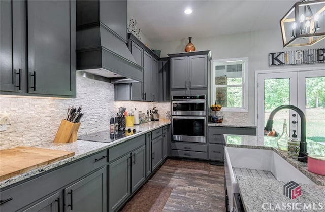 kitchen featuring gray cabinets, tasteful backsplash, sink, hanging light fixtures, and custom exhaust hood