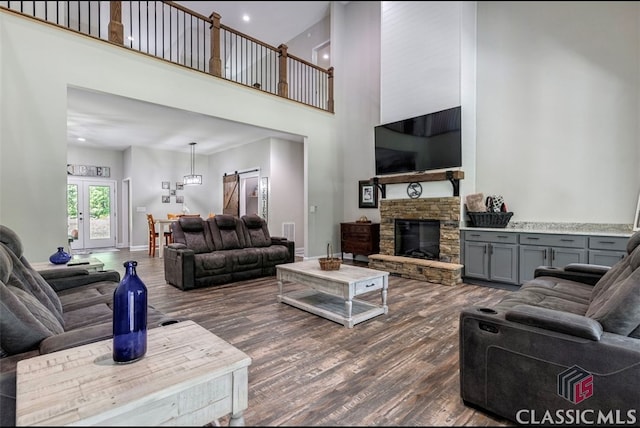 living room with a high ceiling, a stone fireplace, and dark hardwood / wood-style flooring