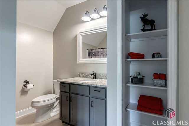 bathroom with built in shelves, lofted ceiling, toilet, and vanity