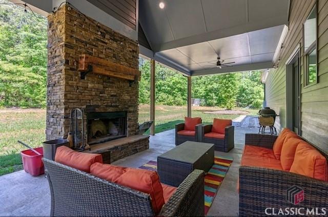 view of patio / terrace featuring ceiling fan and an outdoor living space with a fireplace