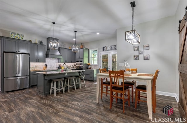 dining area featuring sink, dark wood-type flooring, french doors, and a barn door