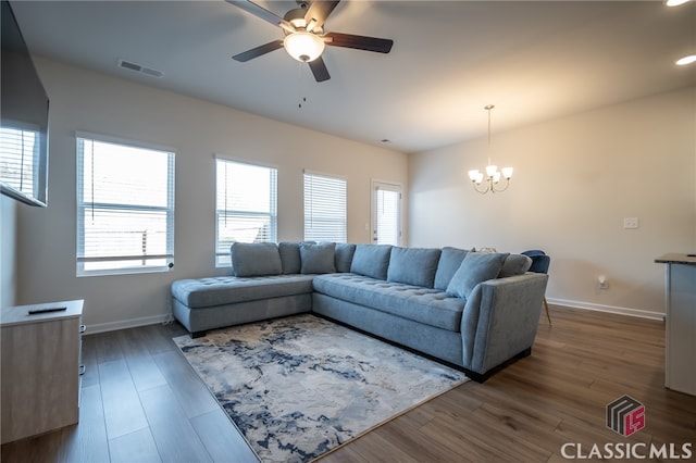 living room featuring ceiling fan with notable chandelier and dark hardwood / wood-style flooring