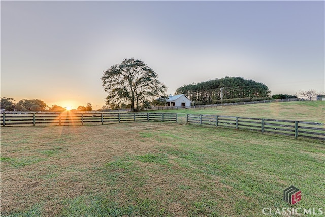 yard at dusk featuring a rural view