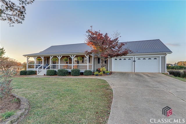 view of front of property featuring a garage, a yard, and covered porch