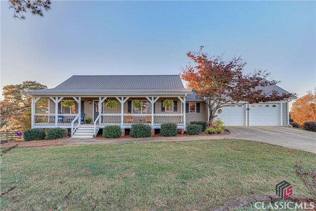 farmhouse featuring a garage, covered porch, and a front yard