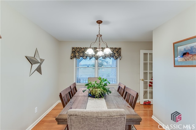 dining space with light wood-type flooring and an inviting chandelier