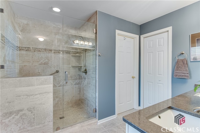 bathroom with a shower with shower door, vanity, and tile patterned flooring