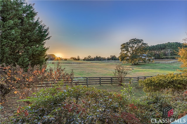 yard at dusk featuring a rural view