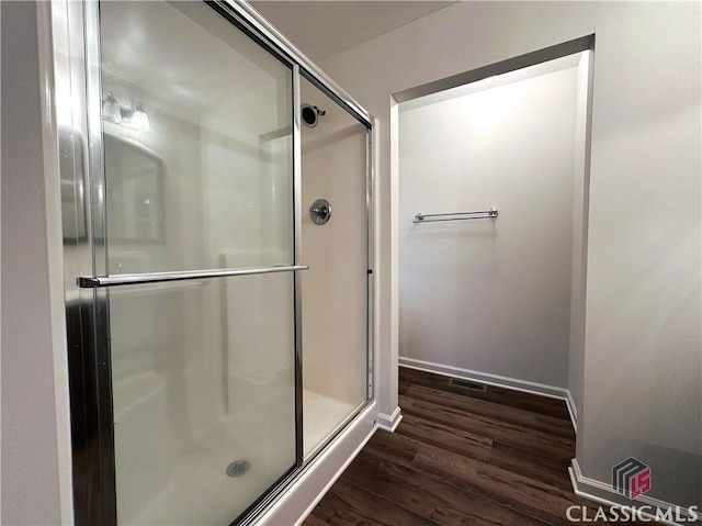 bathroom featuring wood-type flooring and an enclosed shower