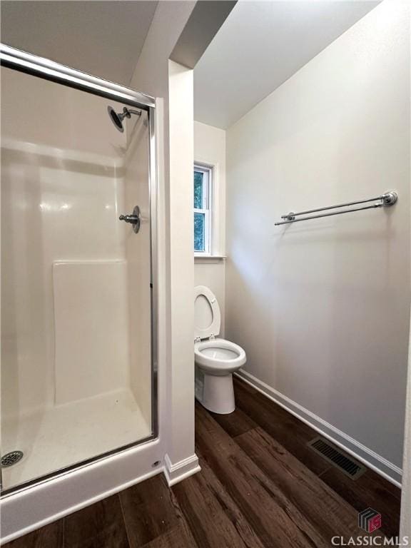 bathroom featuring hardwood / wood-style flooring, toilet, and an enclosed shower