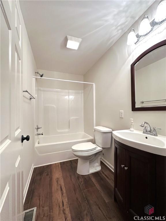 full bathroom featuring bathtub / shower combination, hardwood / wood-style floors, vanity, and toilet