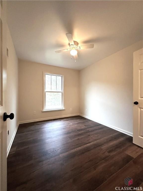 empty room with ceiling fan and dark hardwood / wood-style flooring