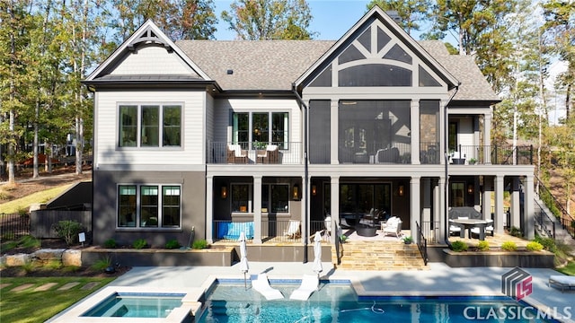 back of property with a pool with hot tub, a patio, and a balcony