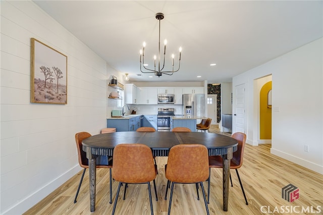 dining area with sink, a notable chandelier, and light hardwood / wood-style flooring