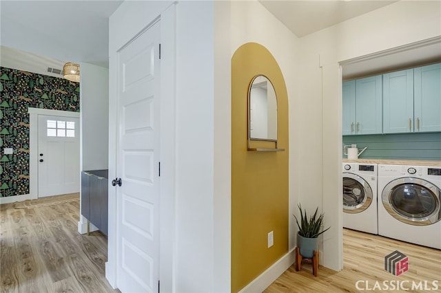 laundry area featuring light hardwood / wood-style flooring, cabinets, and independent washer and dryer