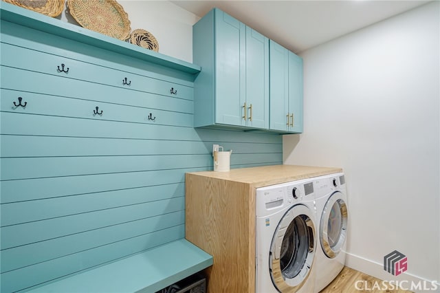 laundry room featuring separate washer and dryer, cabinets, and light wood-type flooring