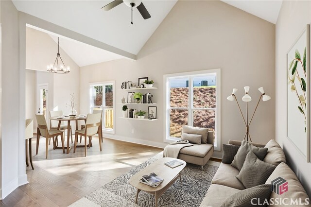 living room featuring plenty of natural light, high vaulted ceiling, hardwood / wood-style floors, and ceiling fan with notable chandelier