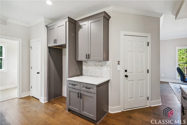 kitchen featuring dark hardwood / wood-style floors, gray cabinets, crown molding, and tasteful backsplash