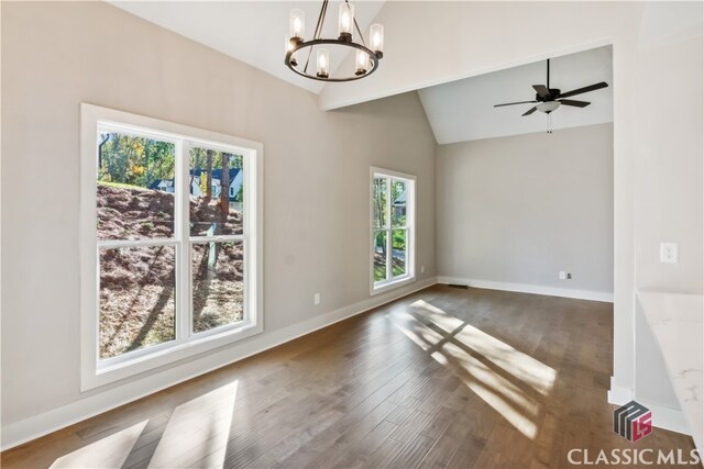 unfurnished room featuring ceiling fan with notable chandelier, dark wood-type flooring, vaulted ceiling, and a healthy amount of sunlight