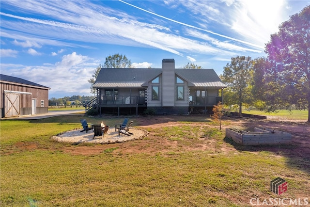 rear view of property with a porch, a fire pit, and a lawn