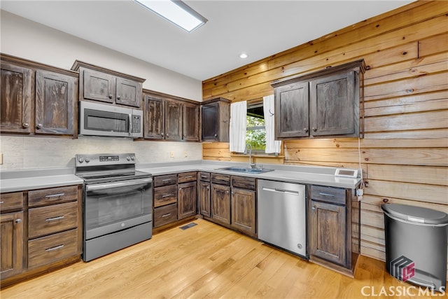 kitchen featuring stainless steel appliances, sink, dark brown cabinets, and light wood-type flooring