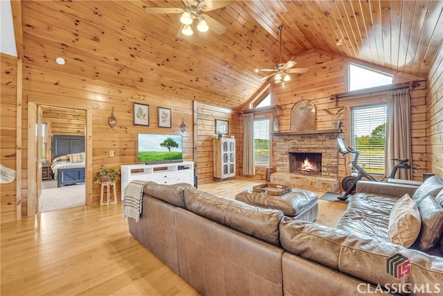 living room with wood ceiling, wooden walls, and a stone fireplace