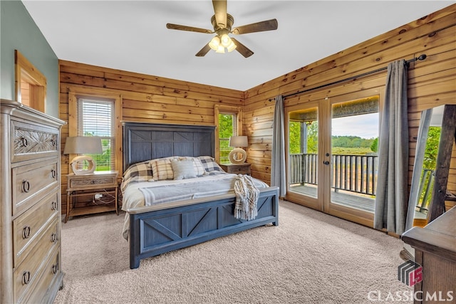 bedroom with light colored carpet, access to exterior, ceiling fan, and wood walls