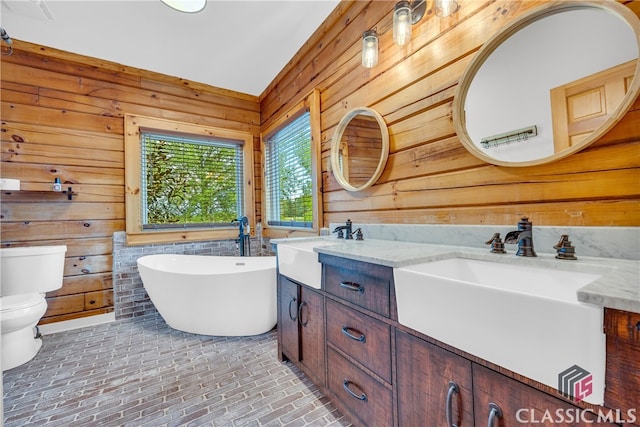 bathroom featuring vanity, a tub, wooden walls, and toilet