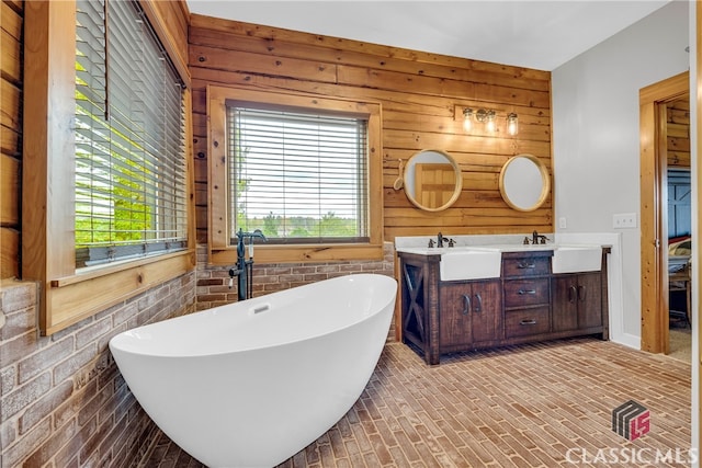 bathroom featuring a bathing tub, vanity, and wood walls