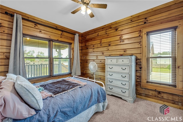 bedroom with ceiling fan, wooden walls, and light carpet