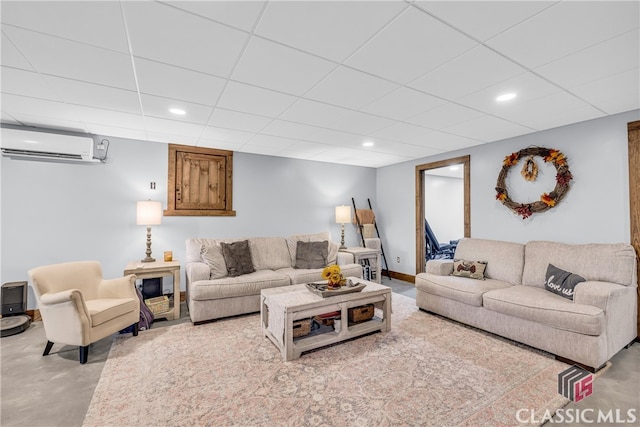 living room featuring an AC wall unit, a drop ceiling, and concrete floors