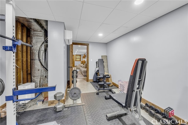 exercise room with a wall mounted air conditioner and a drop ceiling