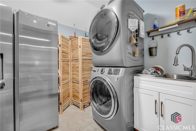 laundry room featuring stacked washer / drying machine, cabinets, and sink