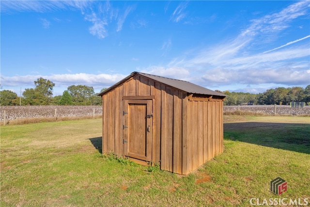 view of outdoor structure with a rural view and a yard