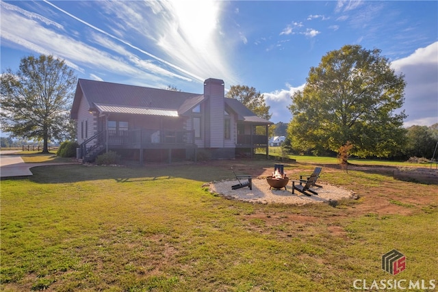 back of house with a yard, a sunroom, and a fire pit