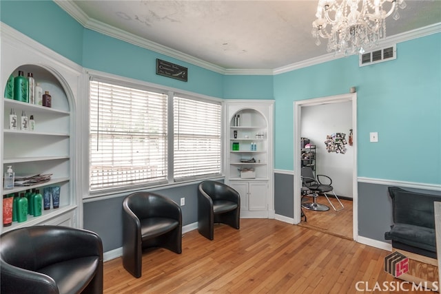 living area with light hardwood / wood-style floors, an inviting chandelier, and ornamental molding