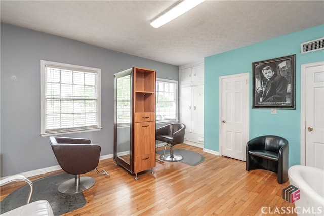 home office with light wood-type flooring and a textured ceiling