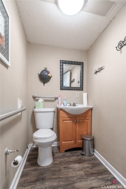 bathroom featuring vanity, toilet, hardwood / wood-style flooring, and a textured ceiling