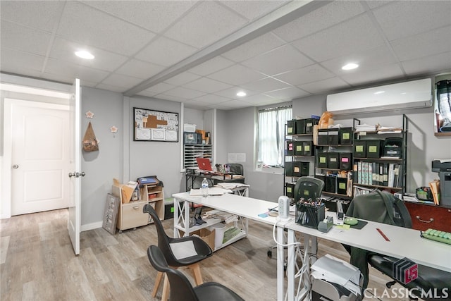 office space with a wall unit AC, light hardwood / wood-style flooring, and a drop ceiling