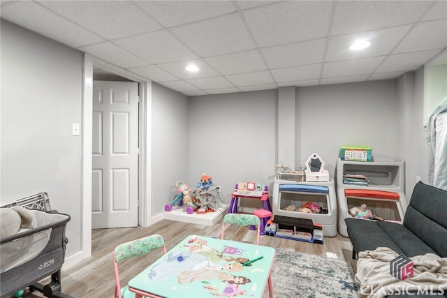 game room with a drop ceiling and light wood-type flooring